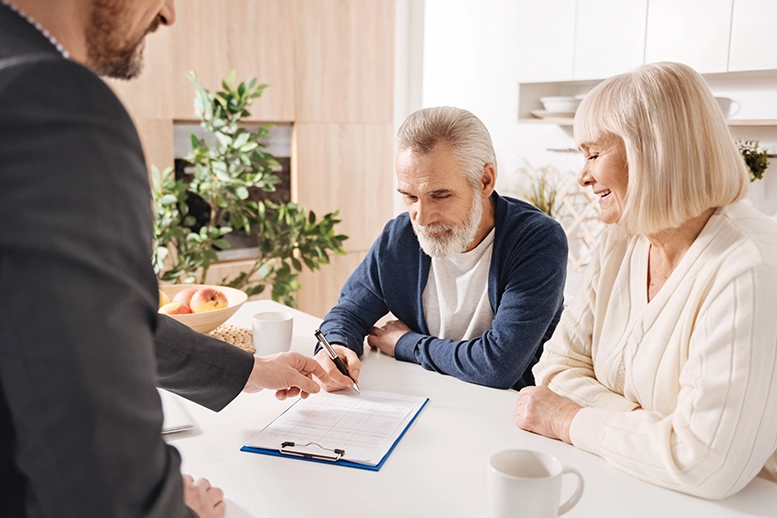 Senior couple discussing documents with a suited professional at a table.