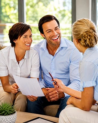 A couple discussing paperwork with a professional in an office setting.