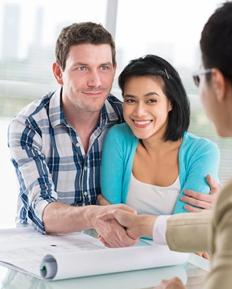 Smiling couple meeting with a professional, shaking hands.