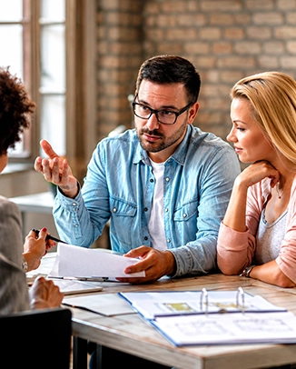 Man and woman discussing documents with an advisor in an office.