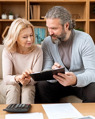Older couple reviewing documents with calculator on a table.