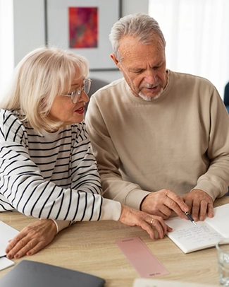 Elderly couple reviewing documents together at a wooden table.